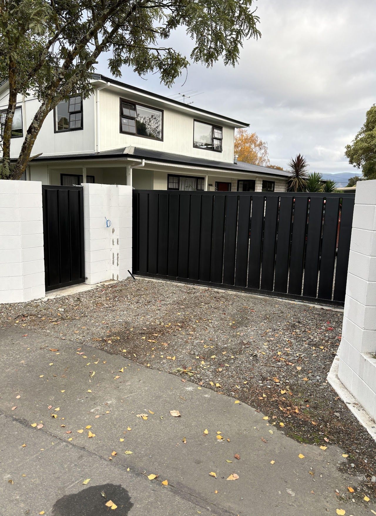 A white house with a black fence and a black gate in front of it.