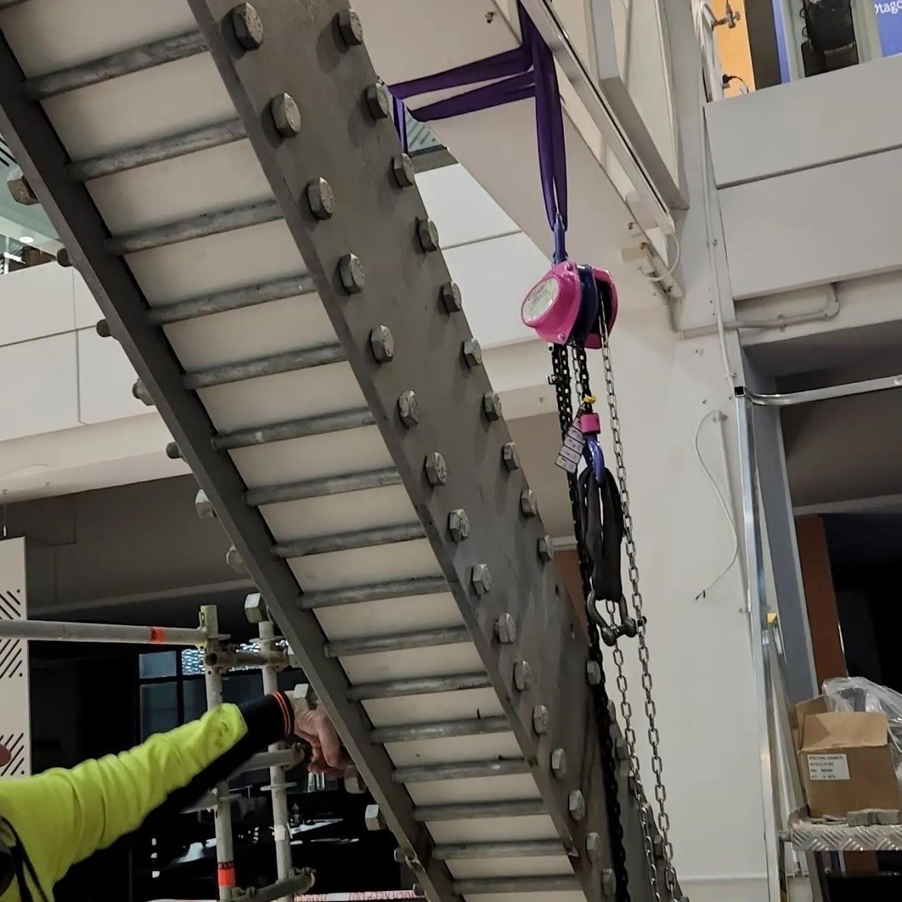 A man in a yellow shirt is working on a conveyor belt.