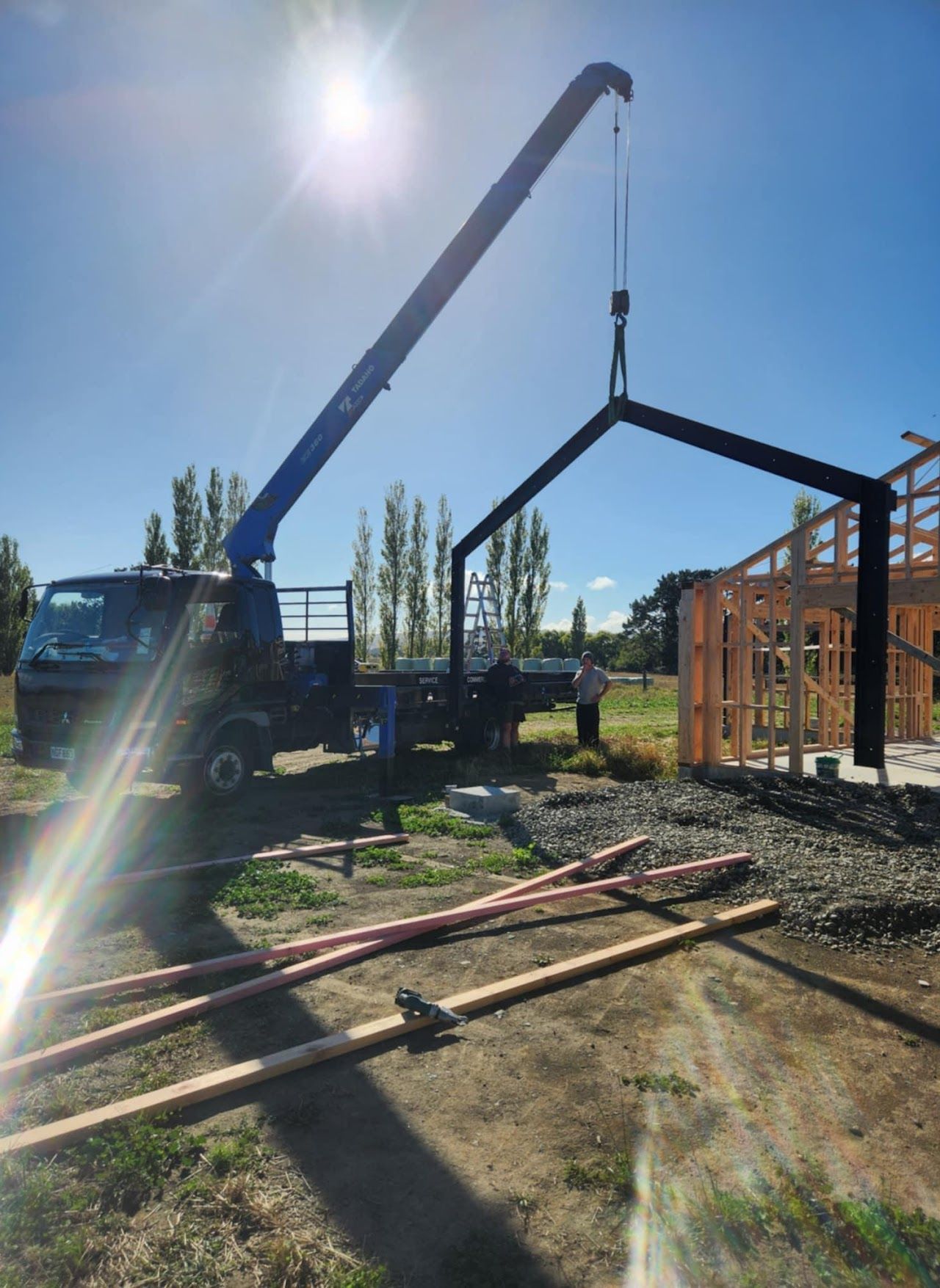 A crane is lifting a metal structure on a construction site.