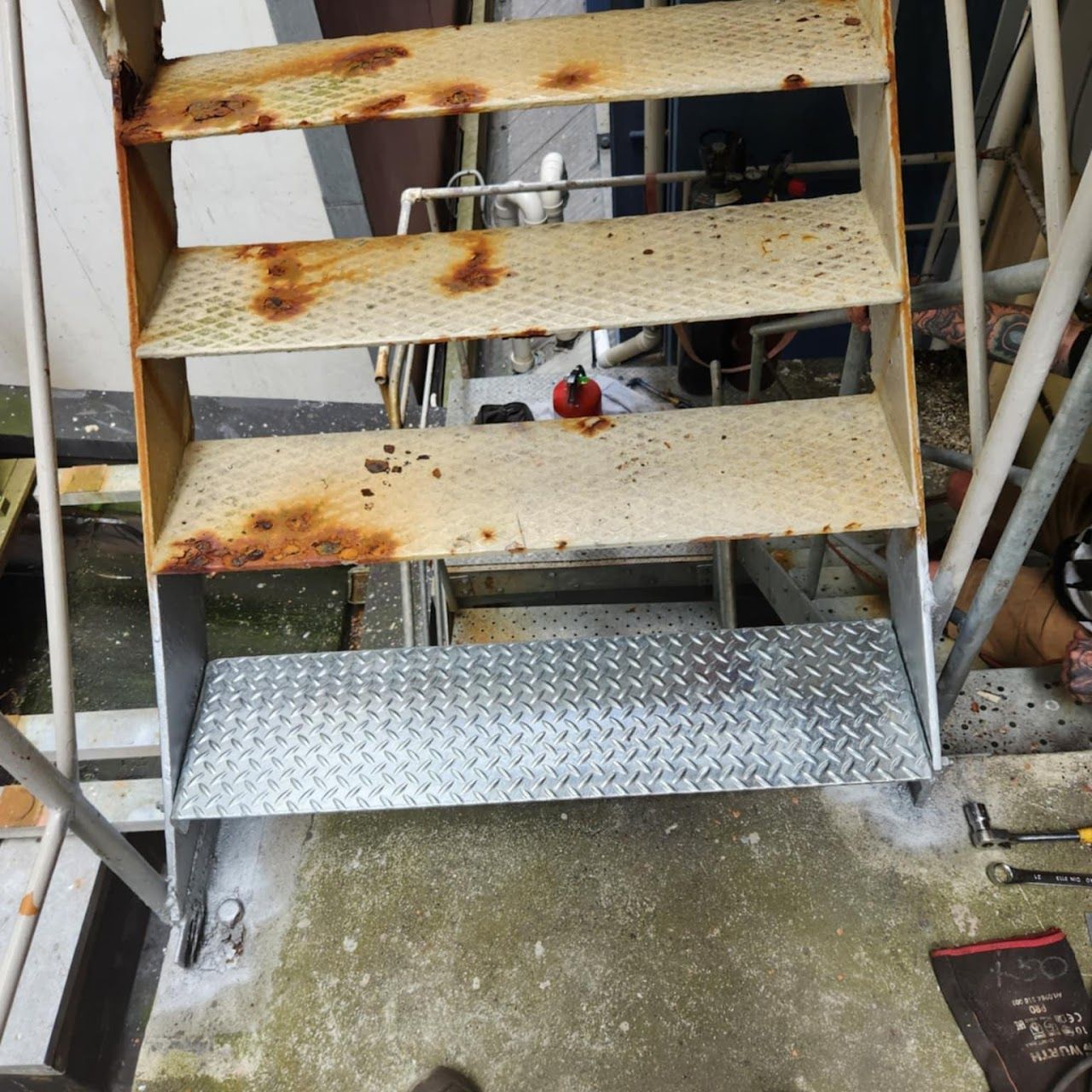 A rusty metal staircase with a metal step.