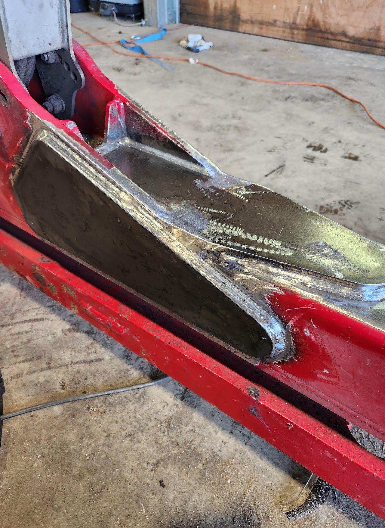 A red boat is being repaired in a garage.