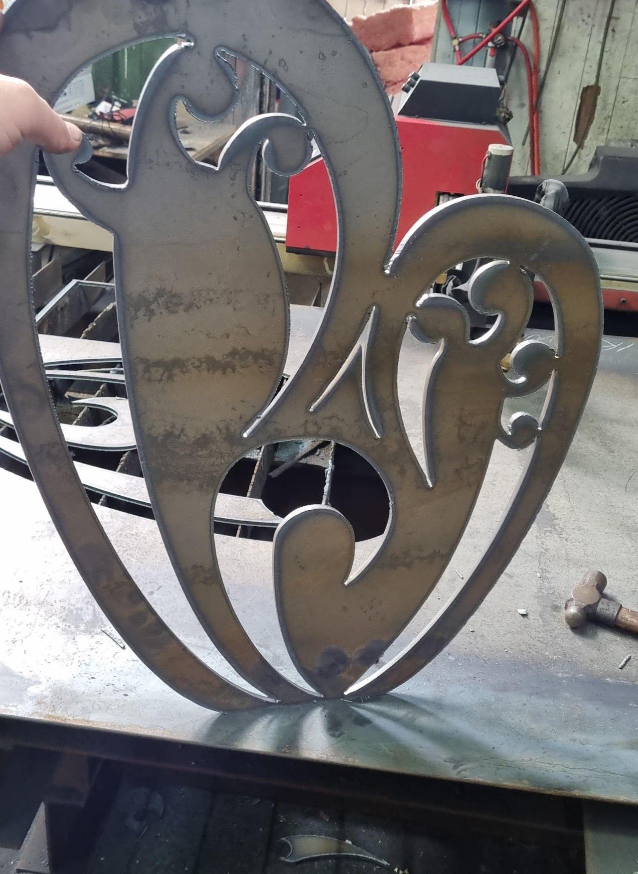 A person is holding a piece of metal in the shape of a heart.