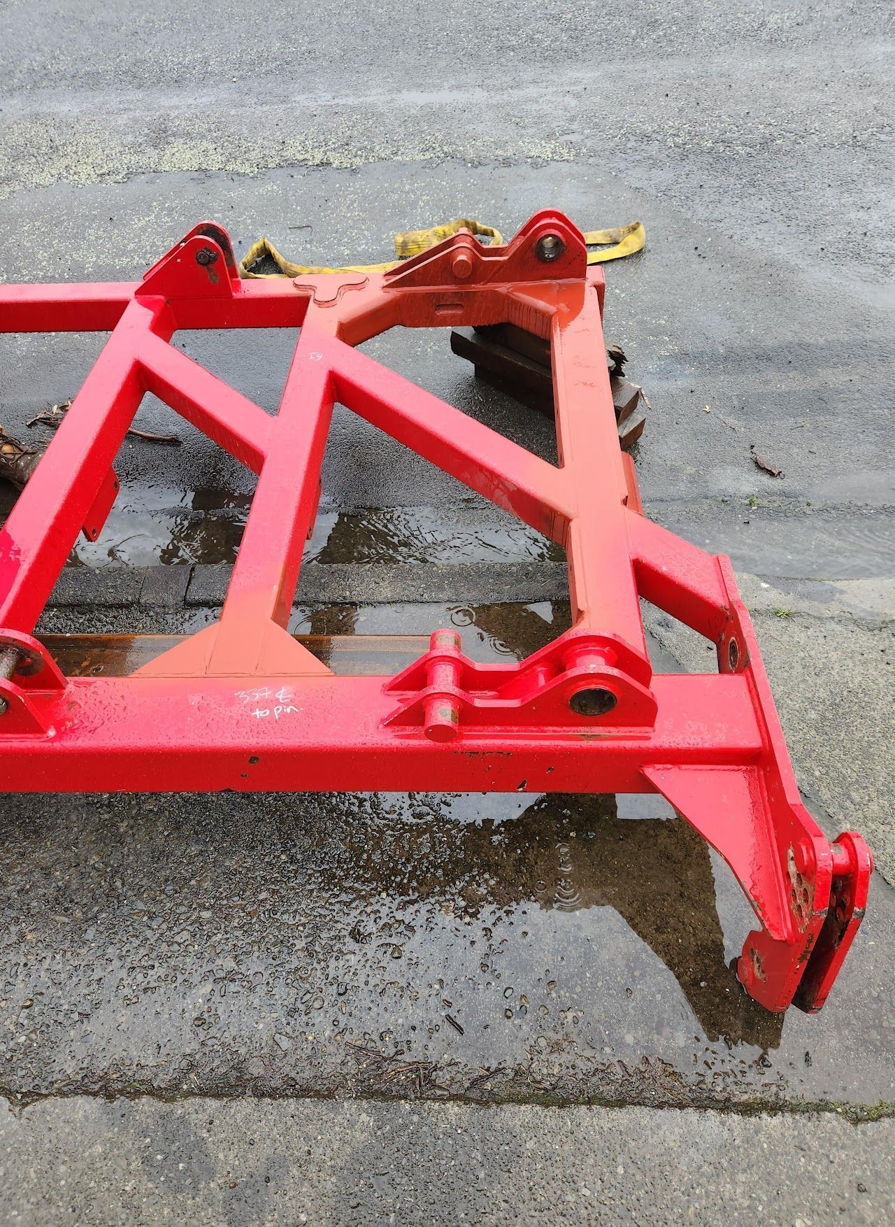 A red metal frame is sitting on a wet concrete surface.