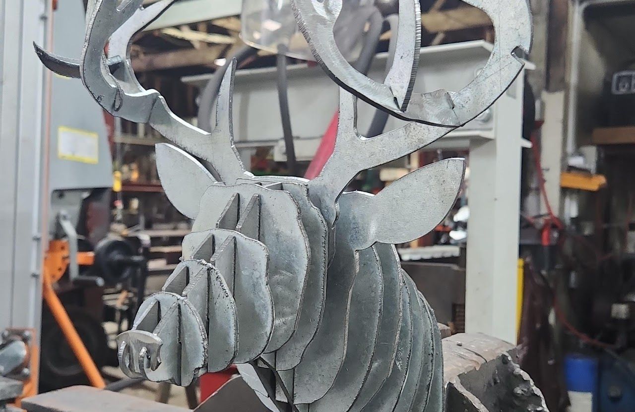 A metal sculpture of a deer head is sitting on a table.