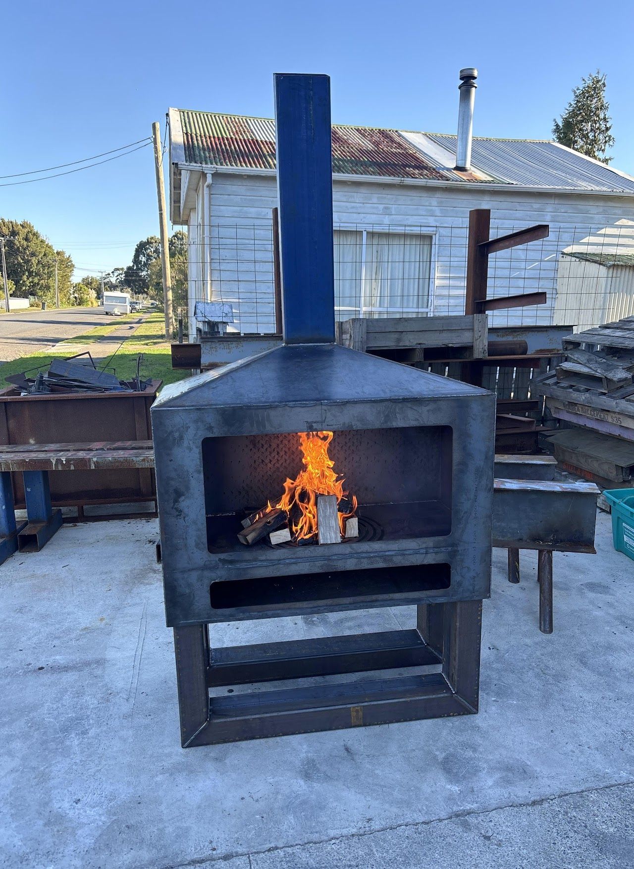 A fireplace with a blue chimney is sitting in front of a white house.