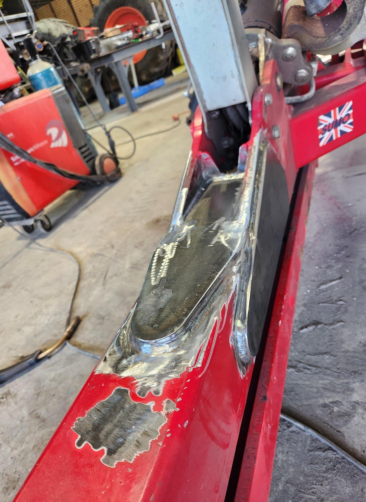 A red piece of metal is being repaired in a garage.