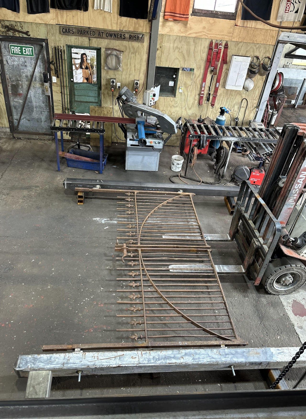 A forklift is carrying a metal fence in a workshop.