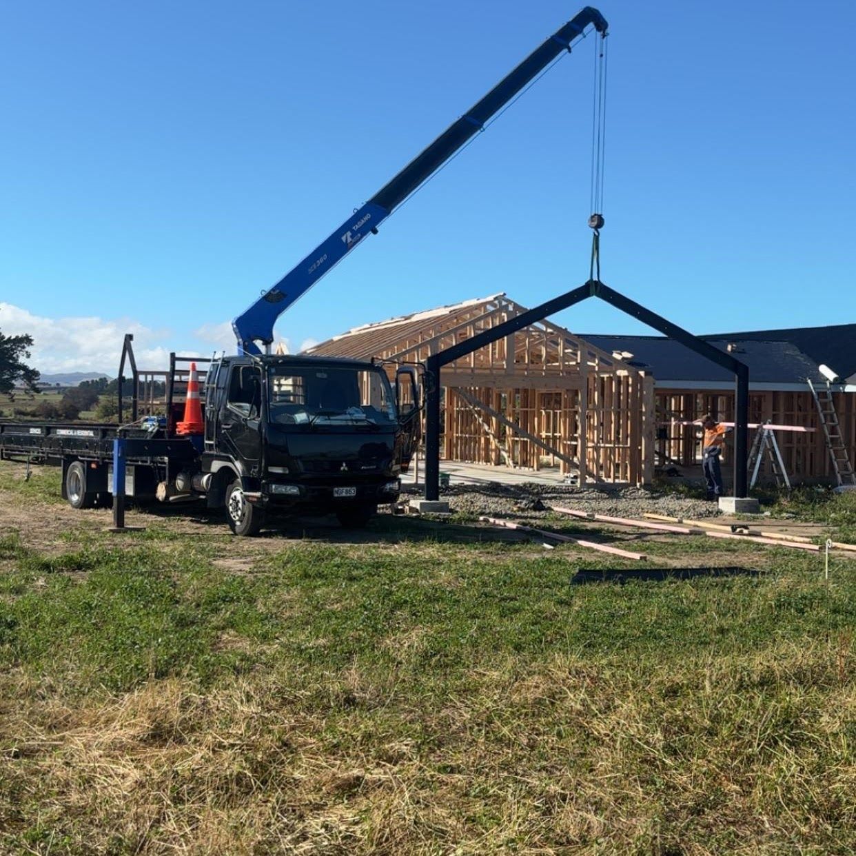 A truck with a crane attached to it is parked in a grassy field.