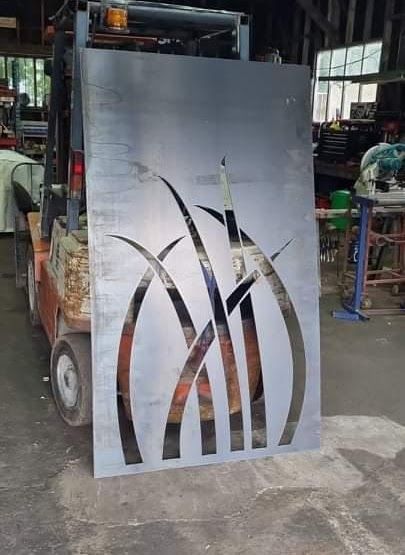A forklift is carrying a large piece of metal with a design on it.