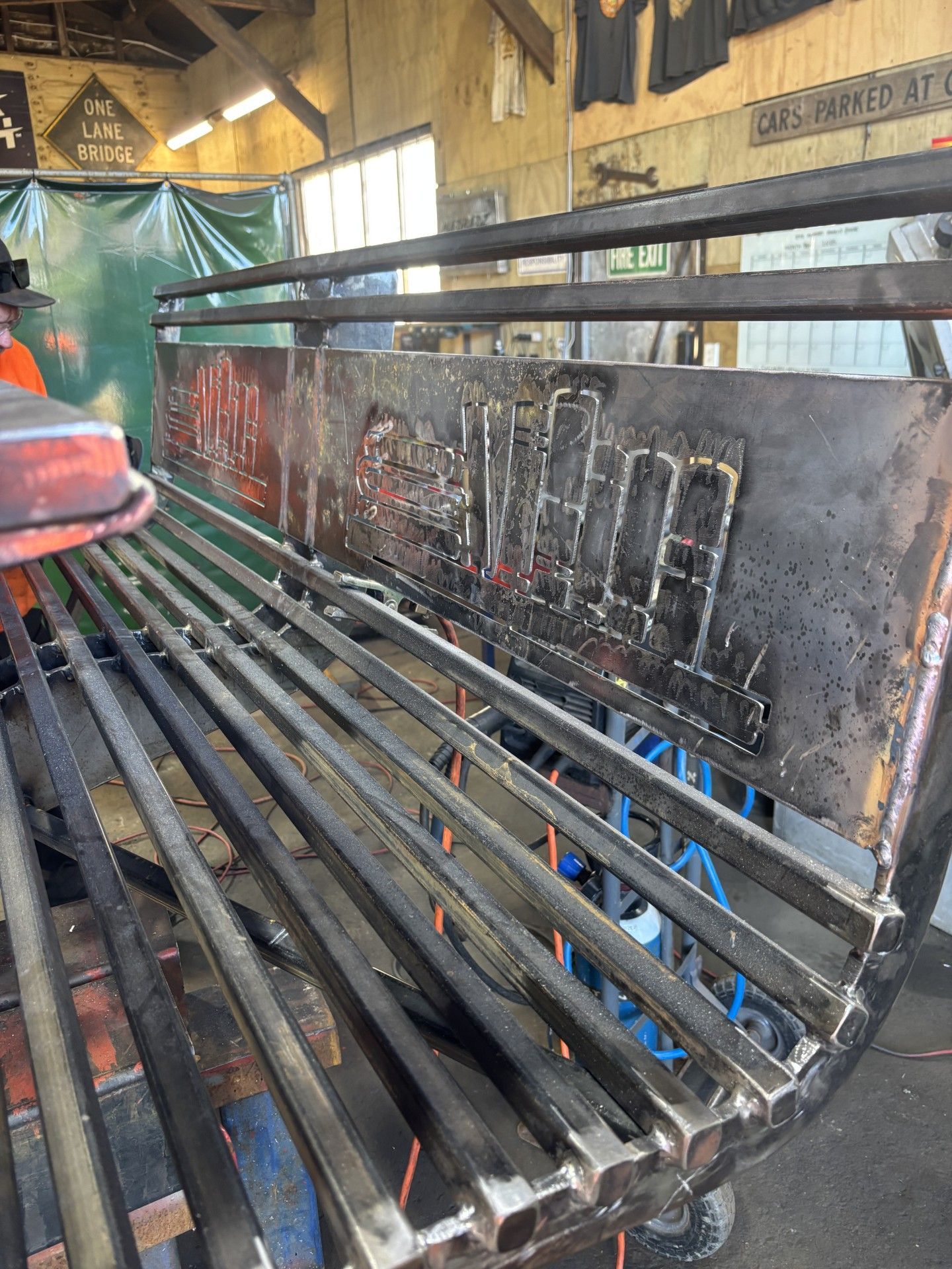 A man is working on a metal bench in a workshop.