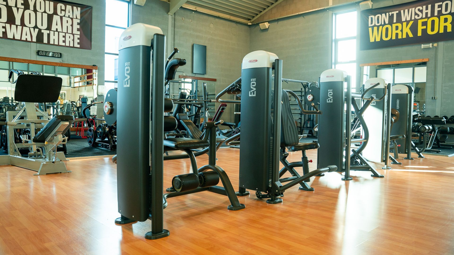 Een sportschool vol met veel fitnessapparatuur op een houten vloer.