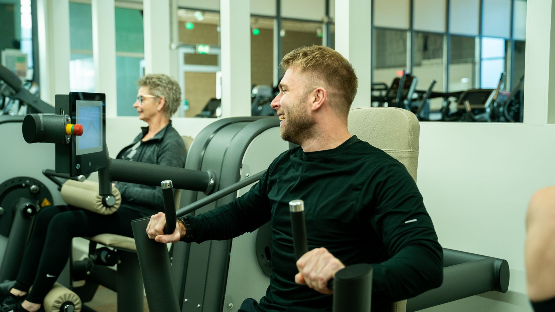 Een man leert een andere man hoe hij een machine moet gebruiken in een sportschool.
