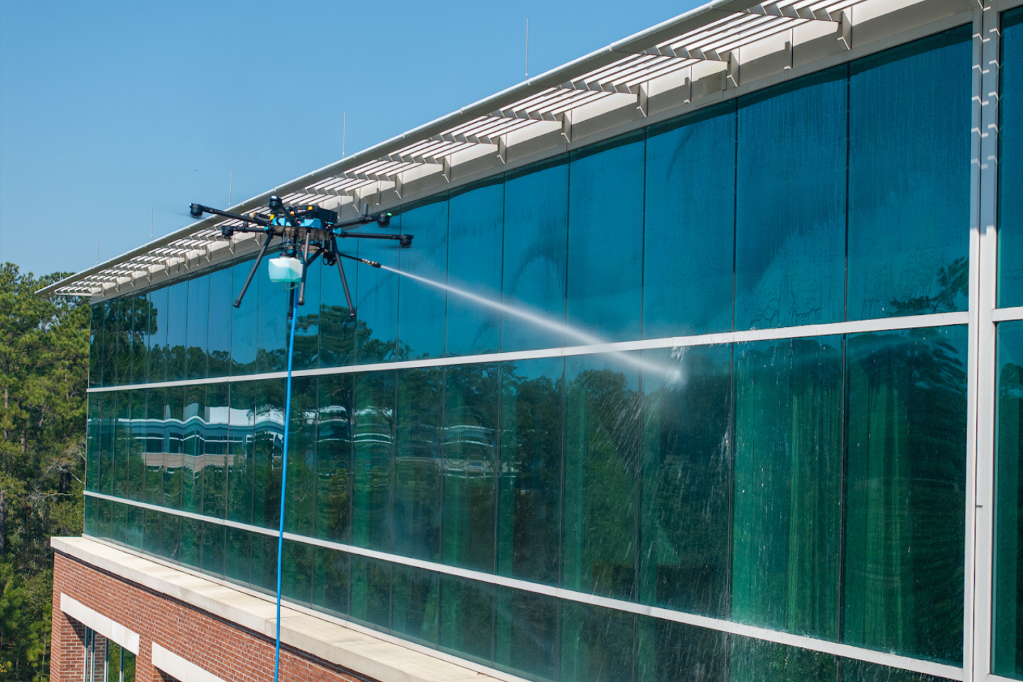 Teal mesh screening on a building exterior with a white roof edge and brick wall below