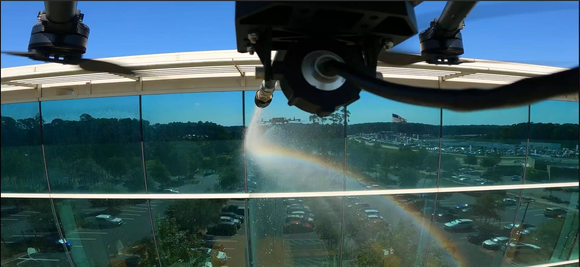Drone spraying water over a forested landscape under a blue sky