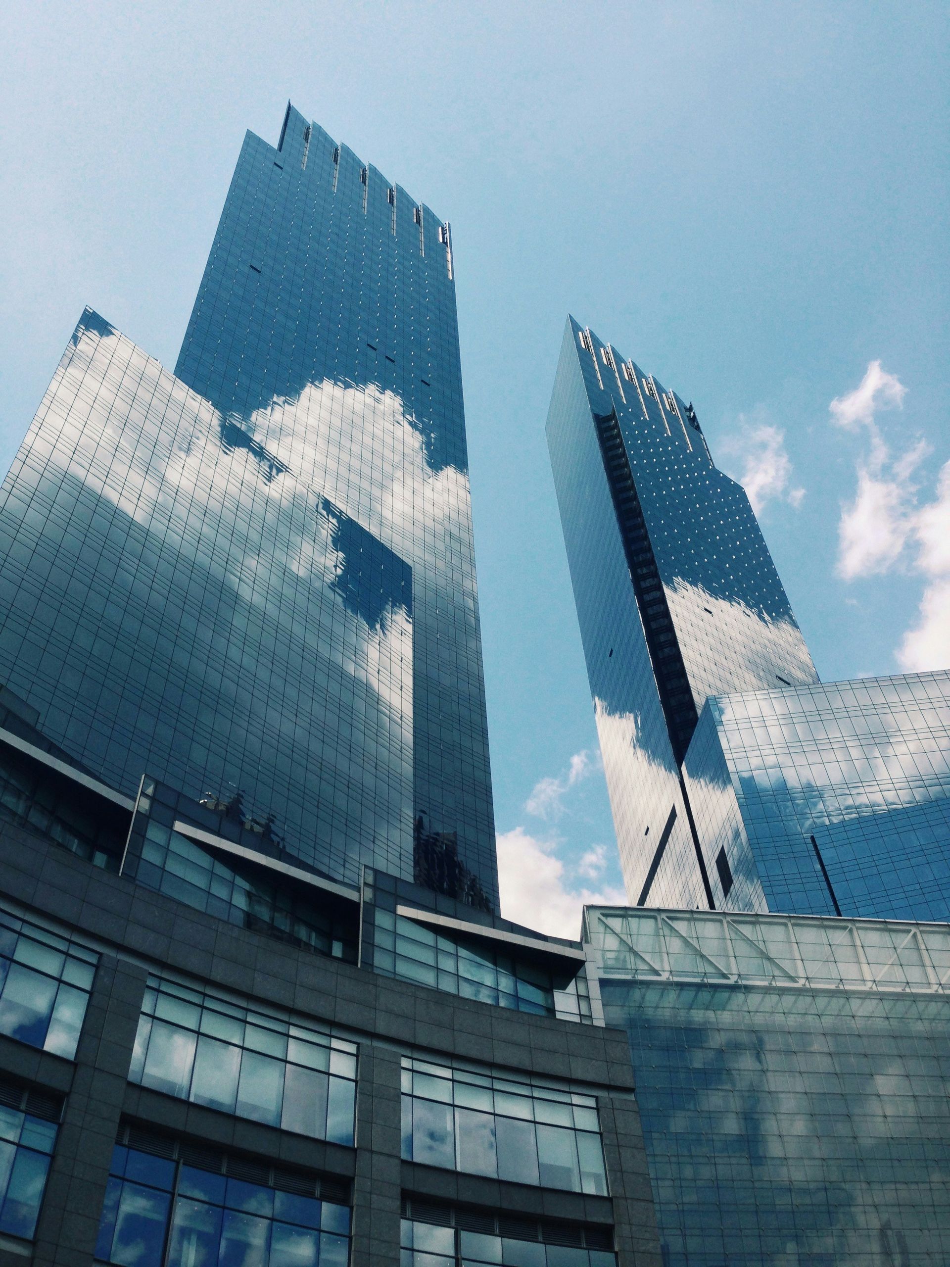 Reflective glass skyscrapers against a blue sky with clouds