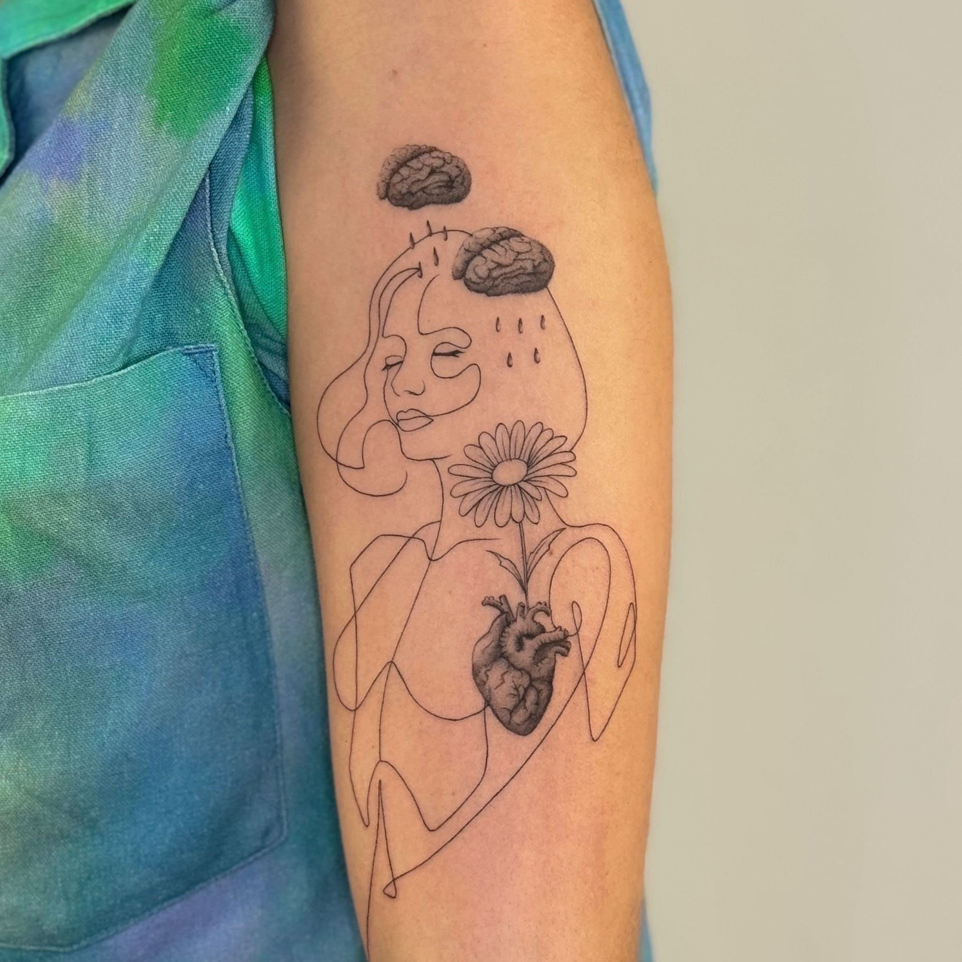 Uma pessoa tem uma tatuagem de uma boneca no braço