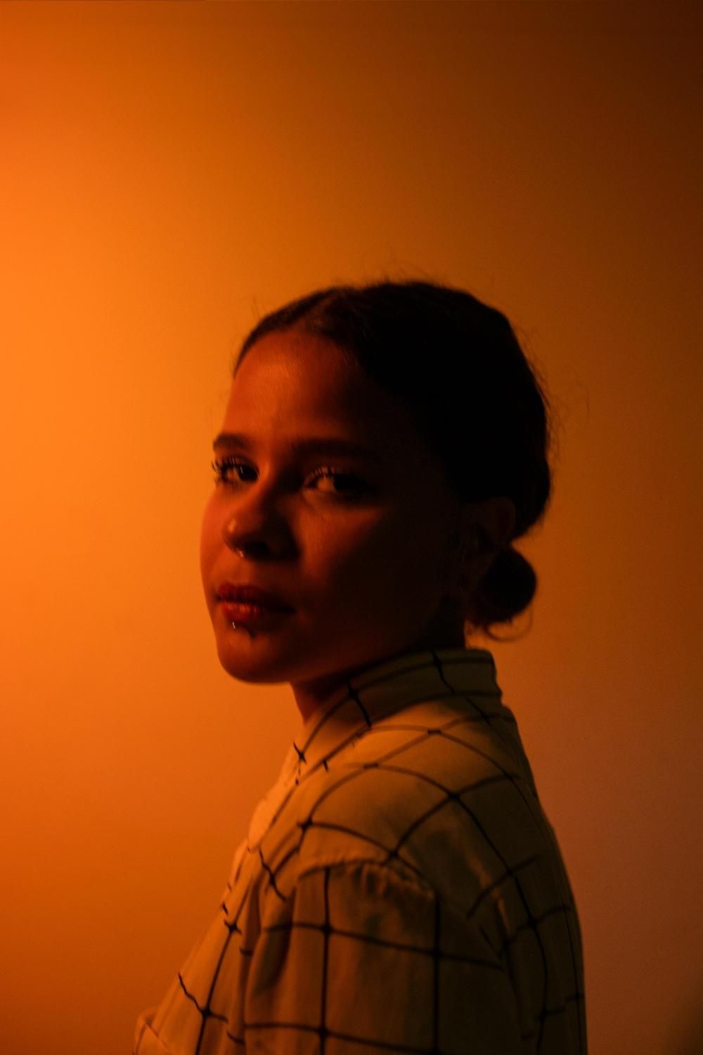 Uma mulher de cabelo curto está vestindo uma camisa preta e brincos.