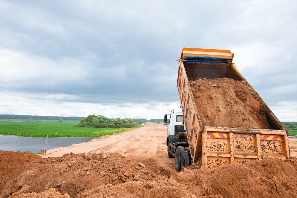Truck Unloading Soil Or Sand At Construction — Plant Hire in Garbutt, QLD