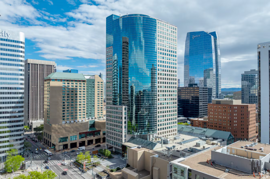 Skyscrapers with reflective blue glass facades dominate a city skyline under a cloudy sky.