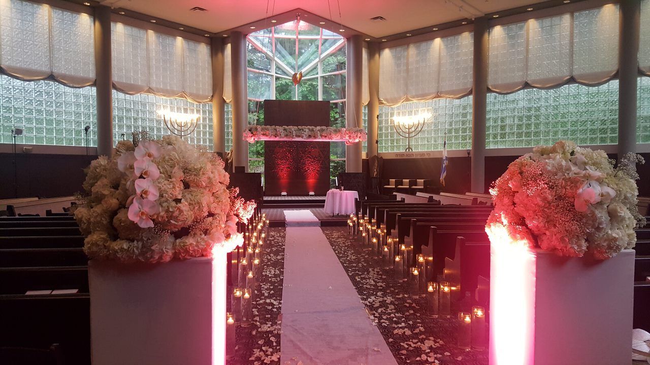 Wedding DJ, Wedding aisle in a chapel with flower arrangements, candles, and red lighting.