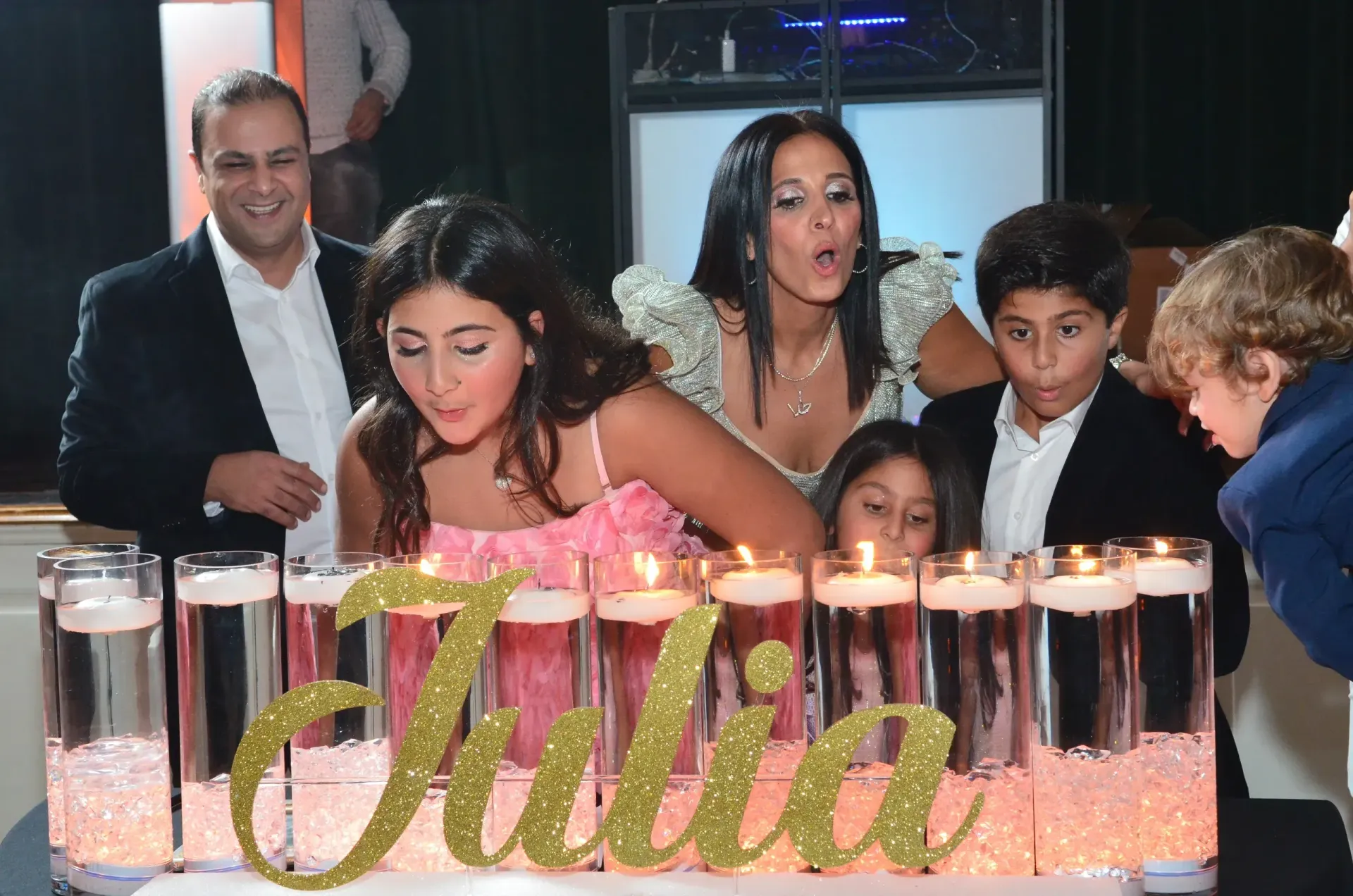 Man in red shirt and glasses at DJ setup, lit with red light.