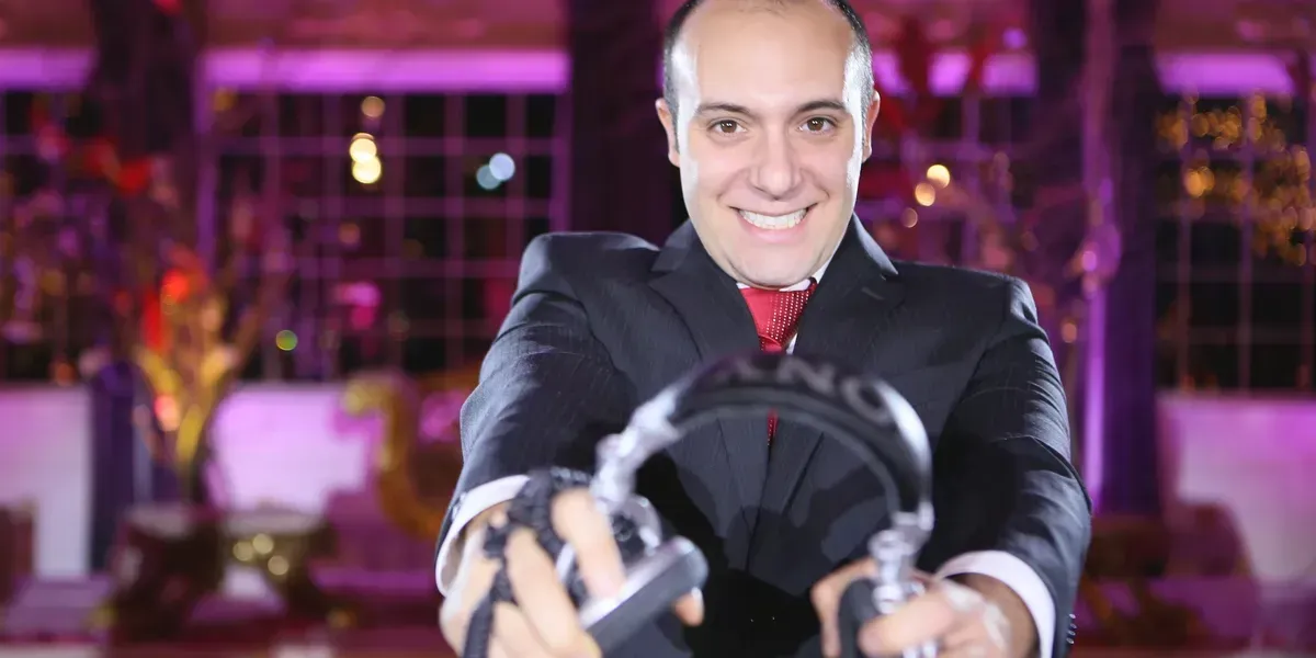Wedding stage with white and pink floral arrangements, white chairs, and purple lighting.