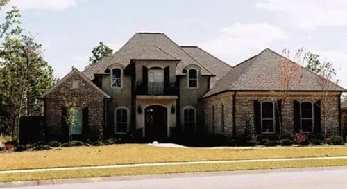 A large house with a gray roof is sitting on top of a lush green lawn.