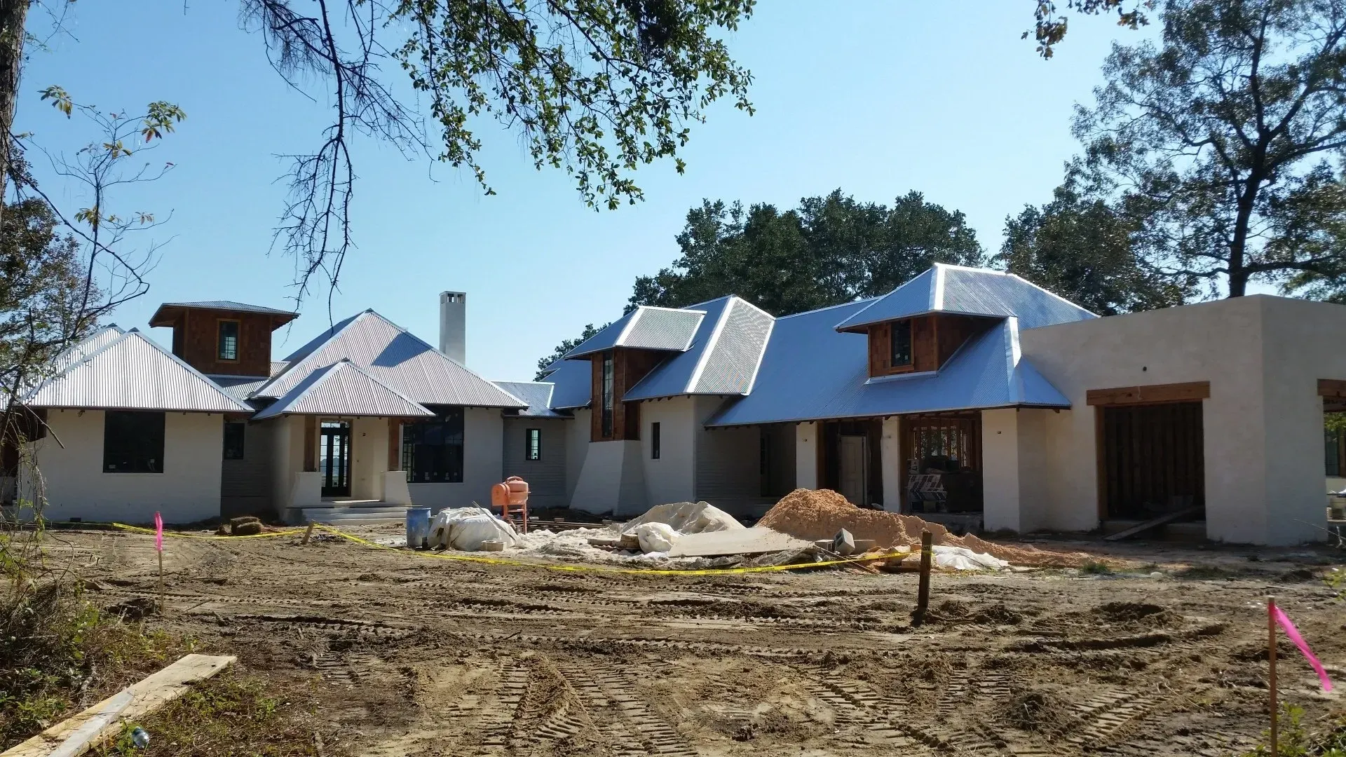 A large house is being built in the middle of a dirt field