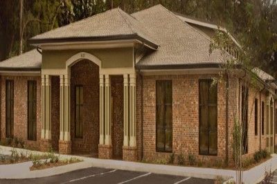 A large brick building with a lot of windows and a parking lot in front of it.