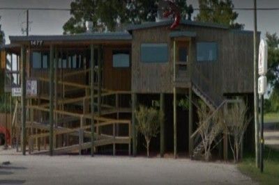 A large wooden house is sitting on top of a dirt road.