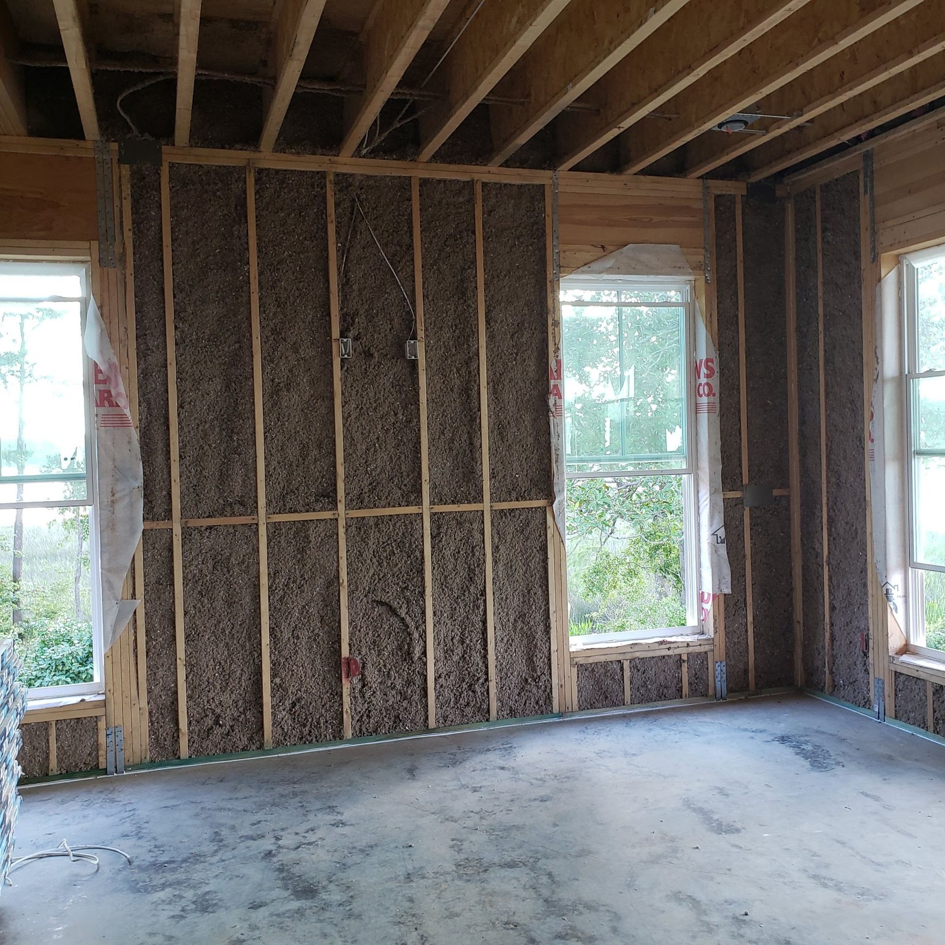An empty room with a wall covered in insulation and a window
