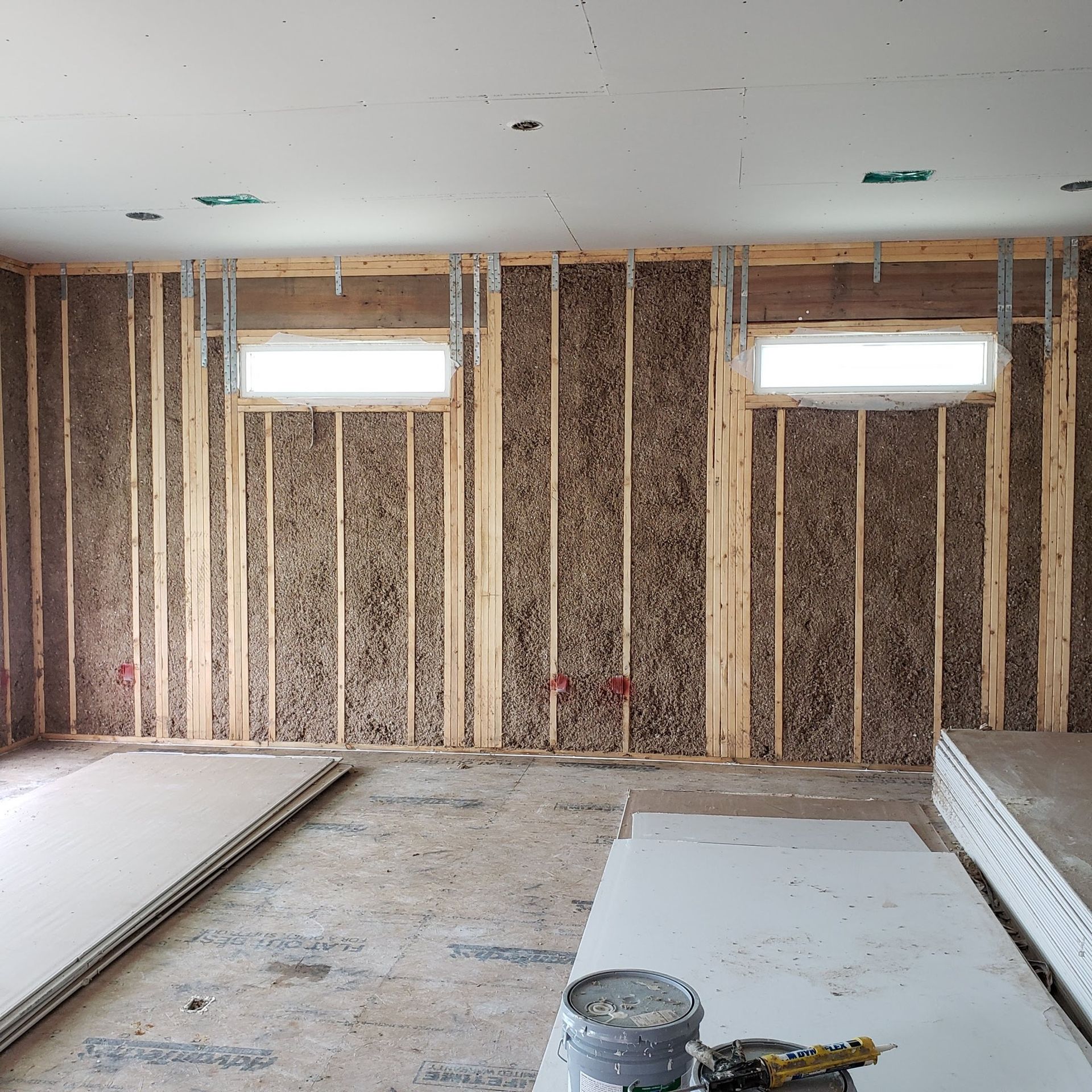 A room under construction with a bucket of paint on the floor