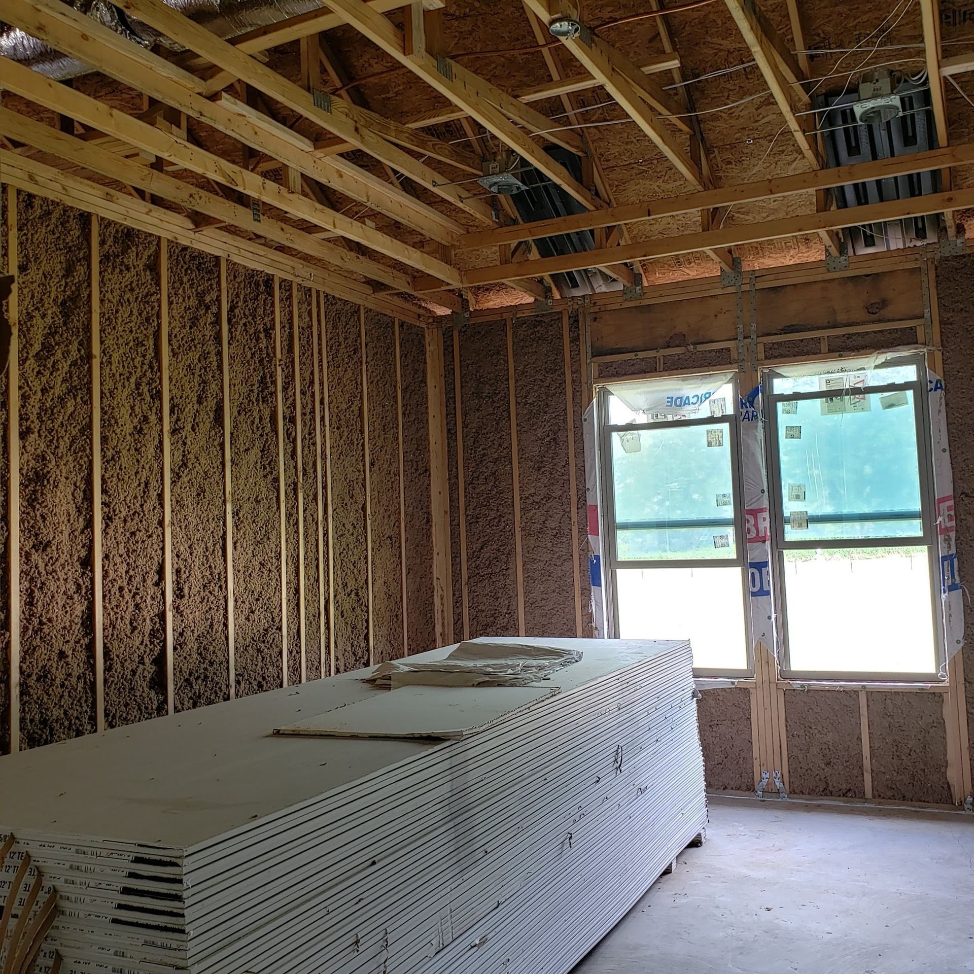 A stack of drywall sits in a room under construction