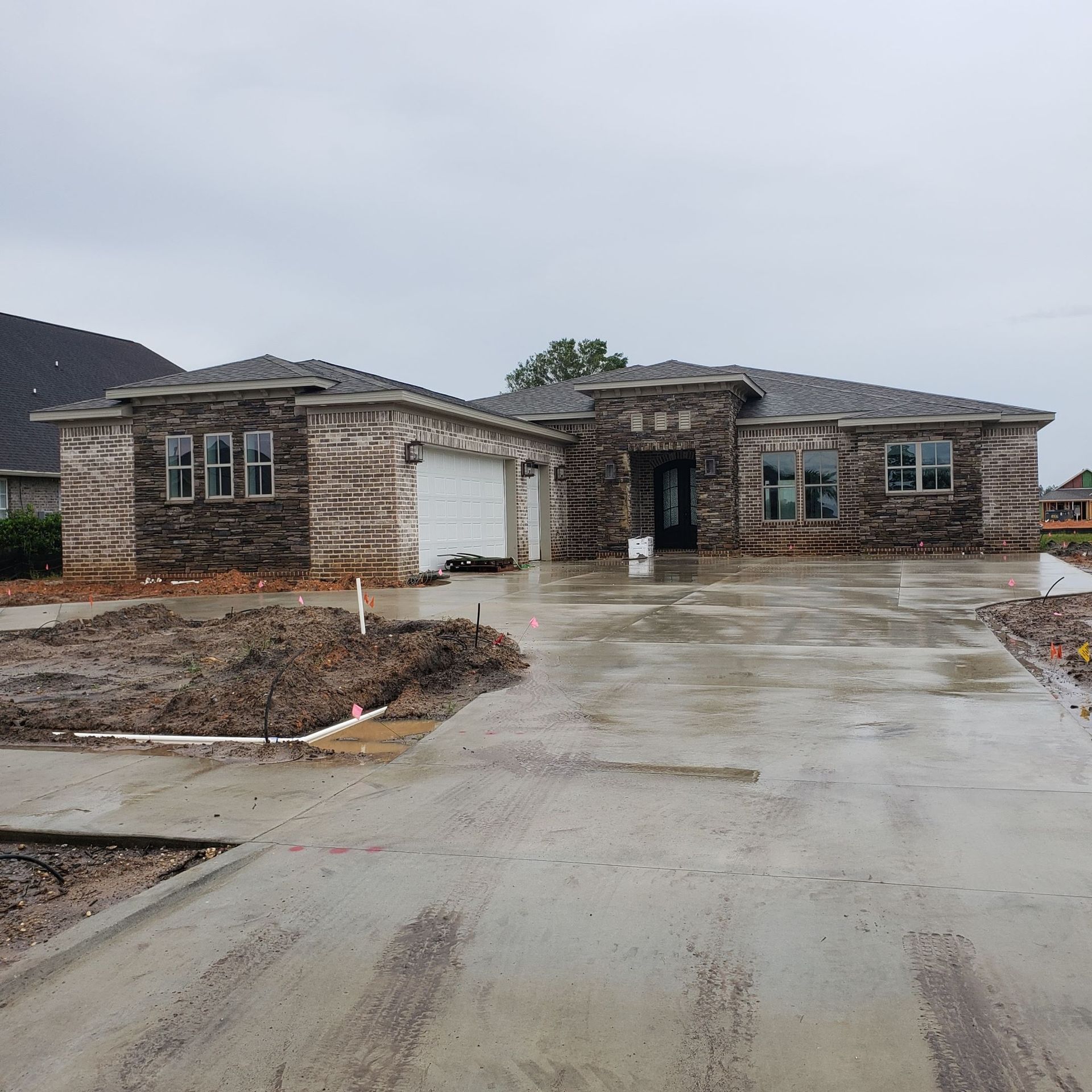 A large stone house with a concrete driveway in front of it