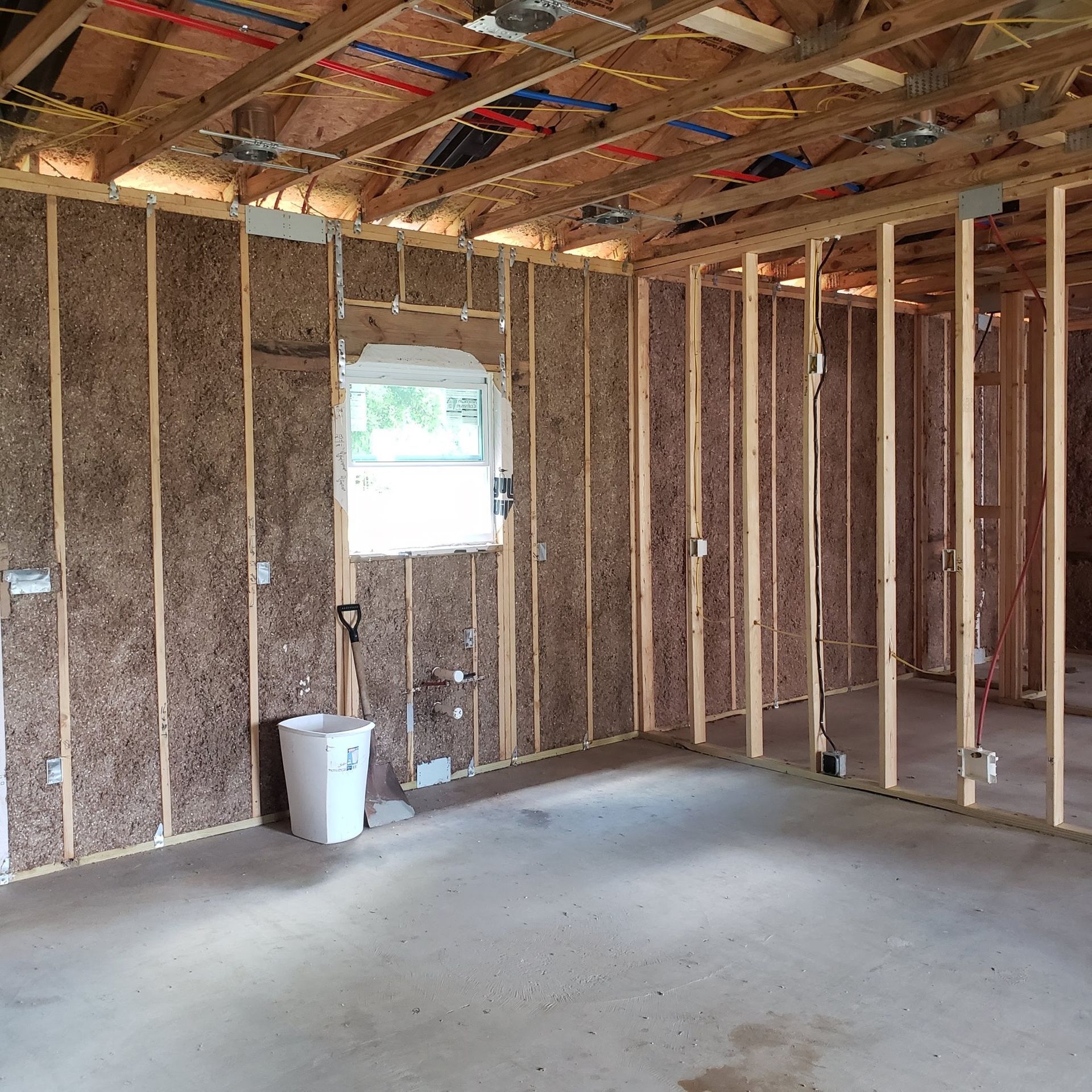 A room with a window and a trash can in it