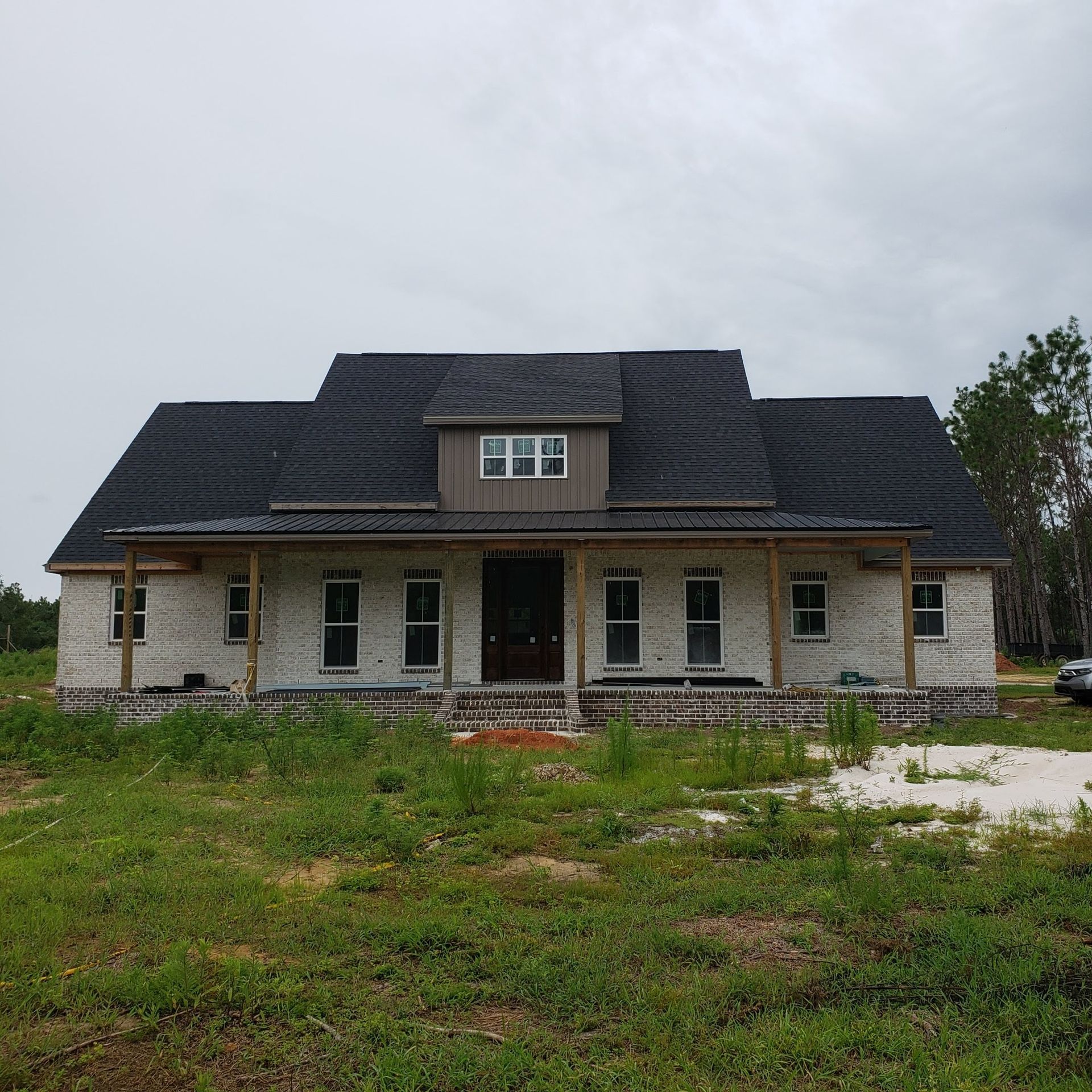 A brick house with a black roof is sitting in the middle of a grassy field