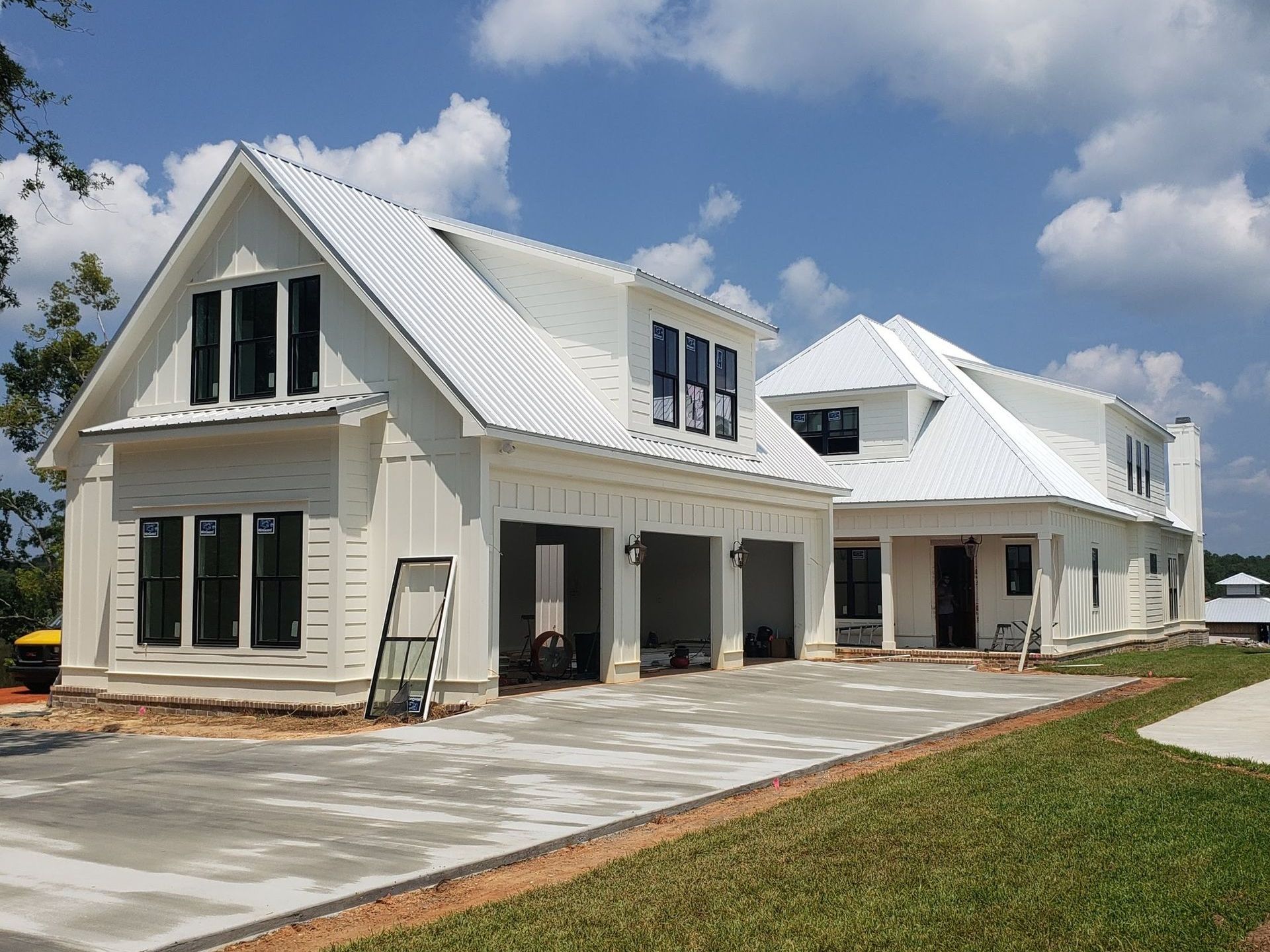 A large white house with a metal roof is being built.