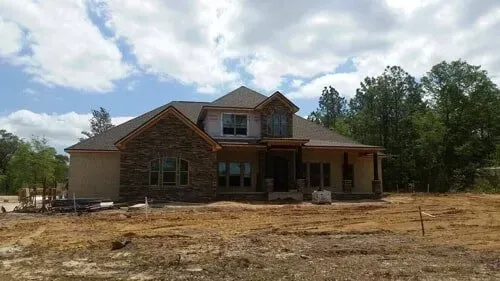 A large house is sitting in the middle of a dirt field.
