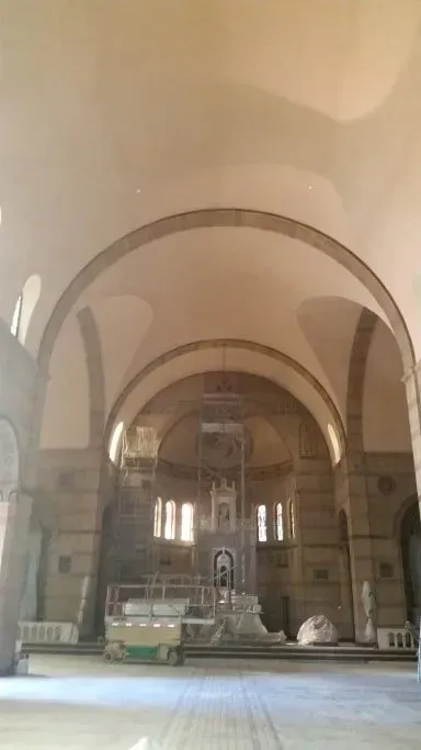 The inside of a church with arches and a large altar.