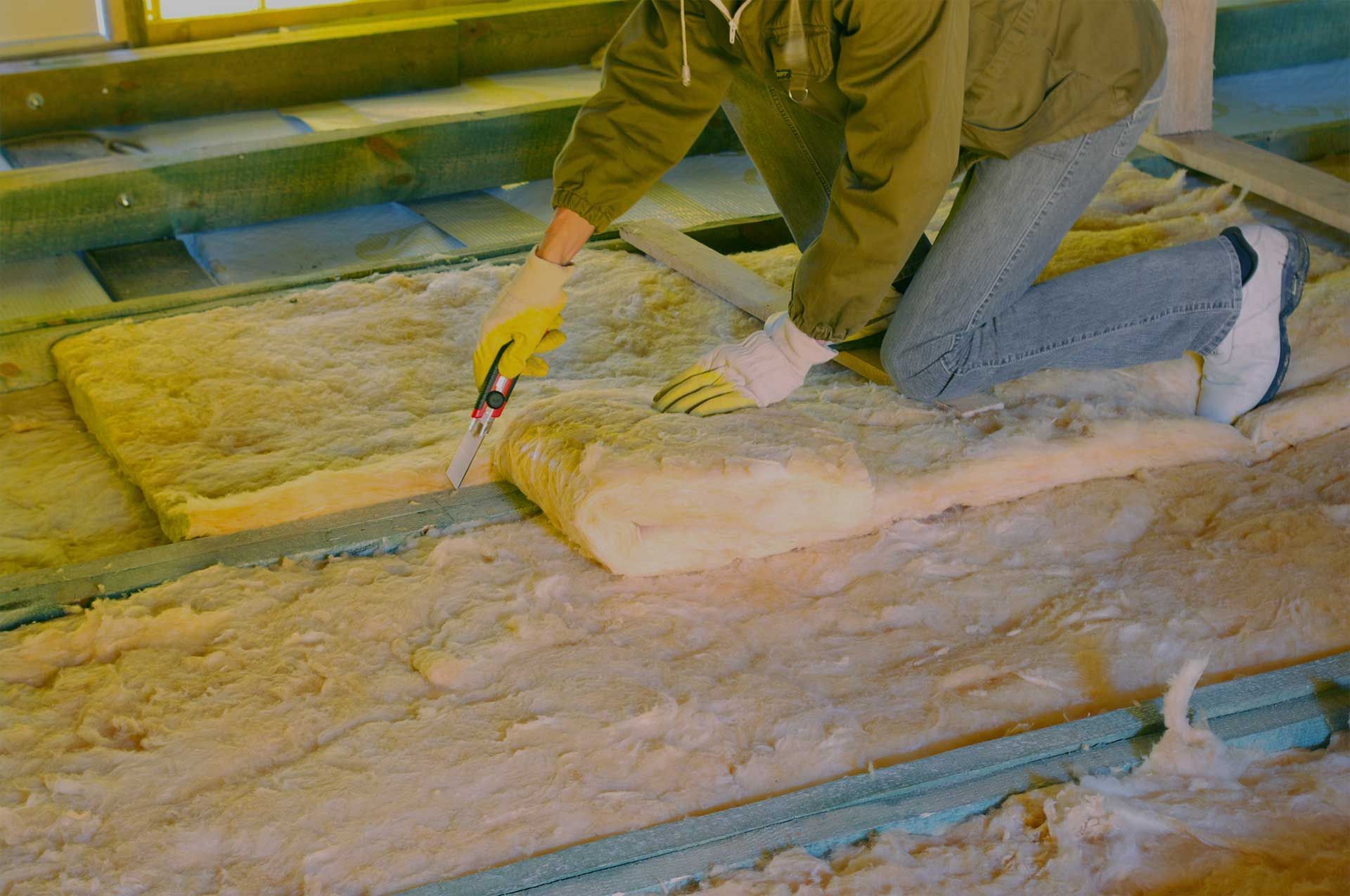 A man is laying insulation on the floor of a house.