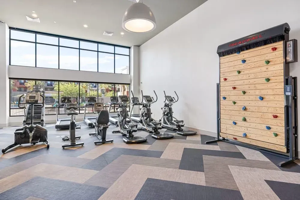 Gym with cardio equipment and a climbing wall.