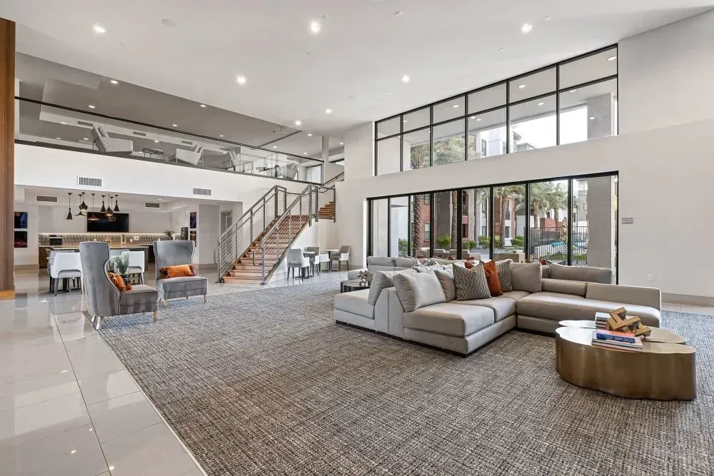 Spacious lobby with sectional sofa, staircase, large windows, and a seating area.