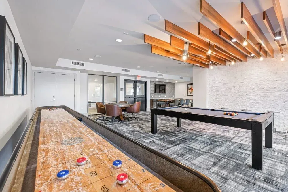 Game room with shuffleboard, pool table, and seating area.