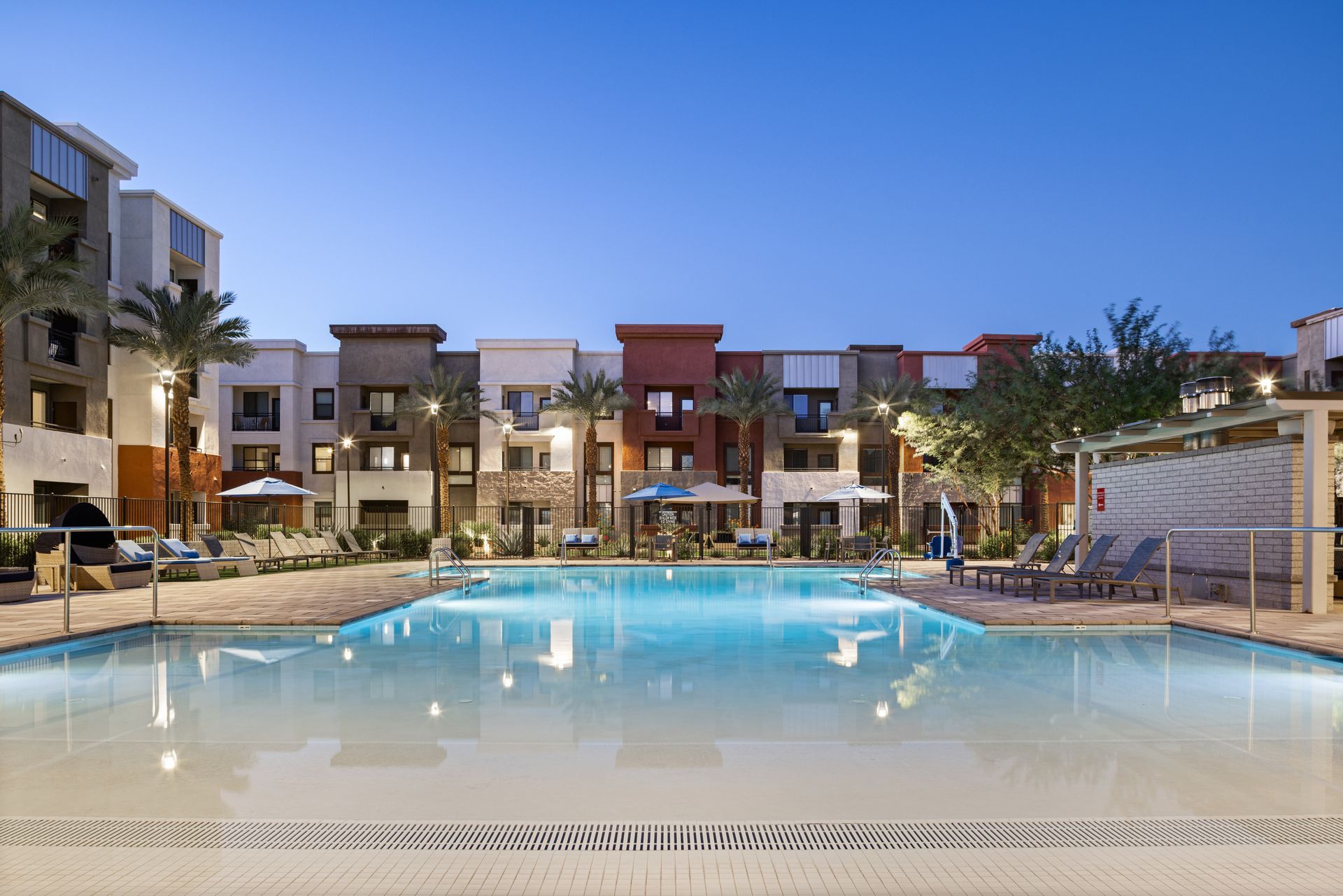 Modern apartment courtyard with a lit swimming pool at dusk