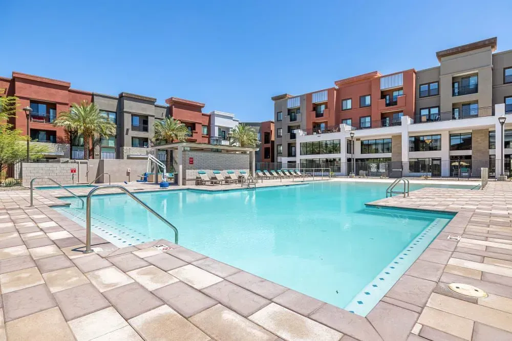 Swimming pool at modern apartment complex on a sunny day.