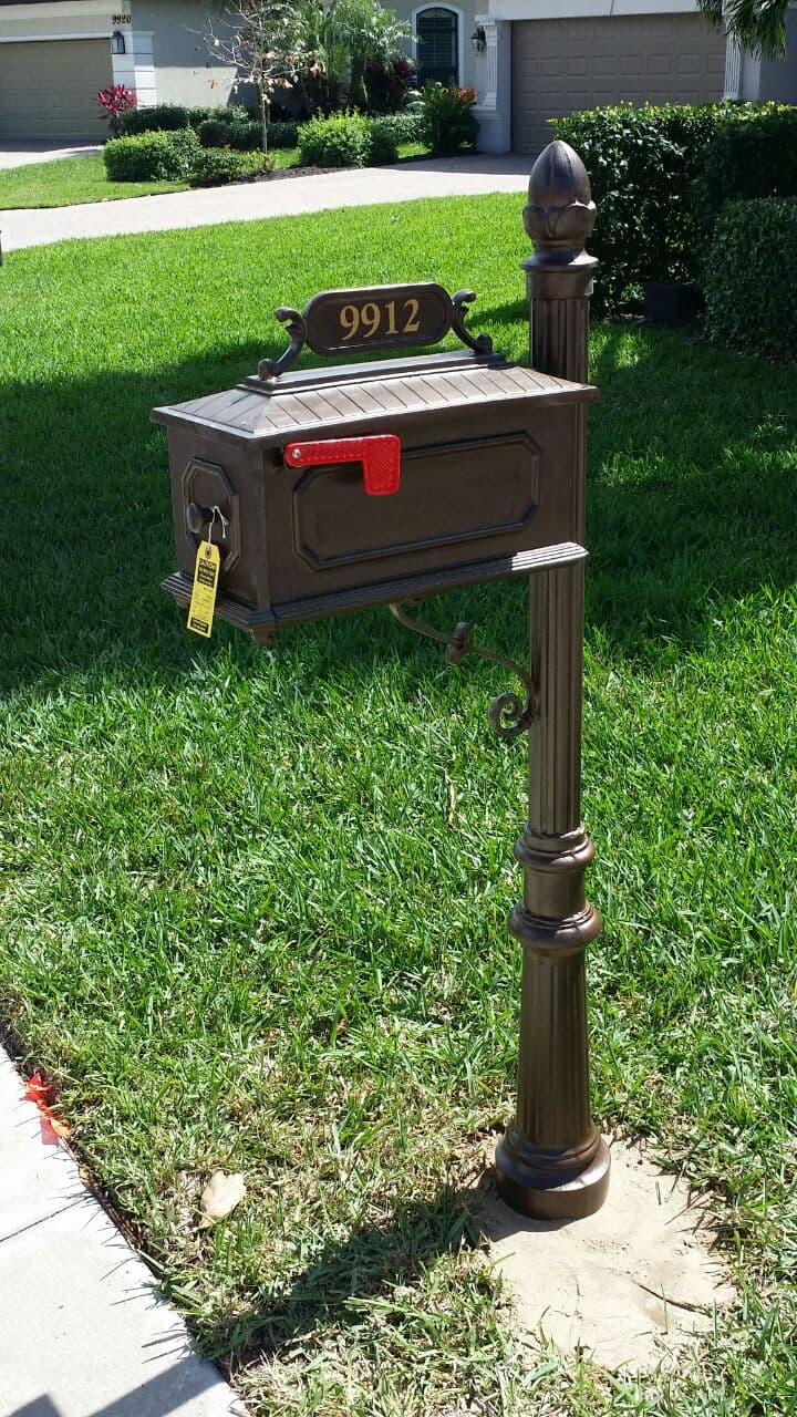 A mailbox is sitting in the grass in front of a house.