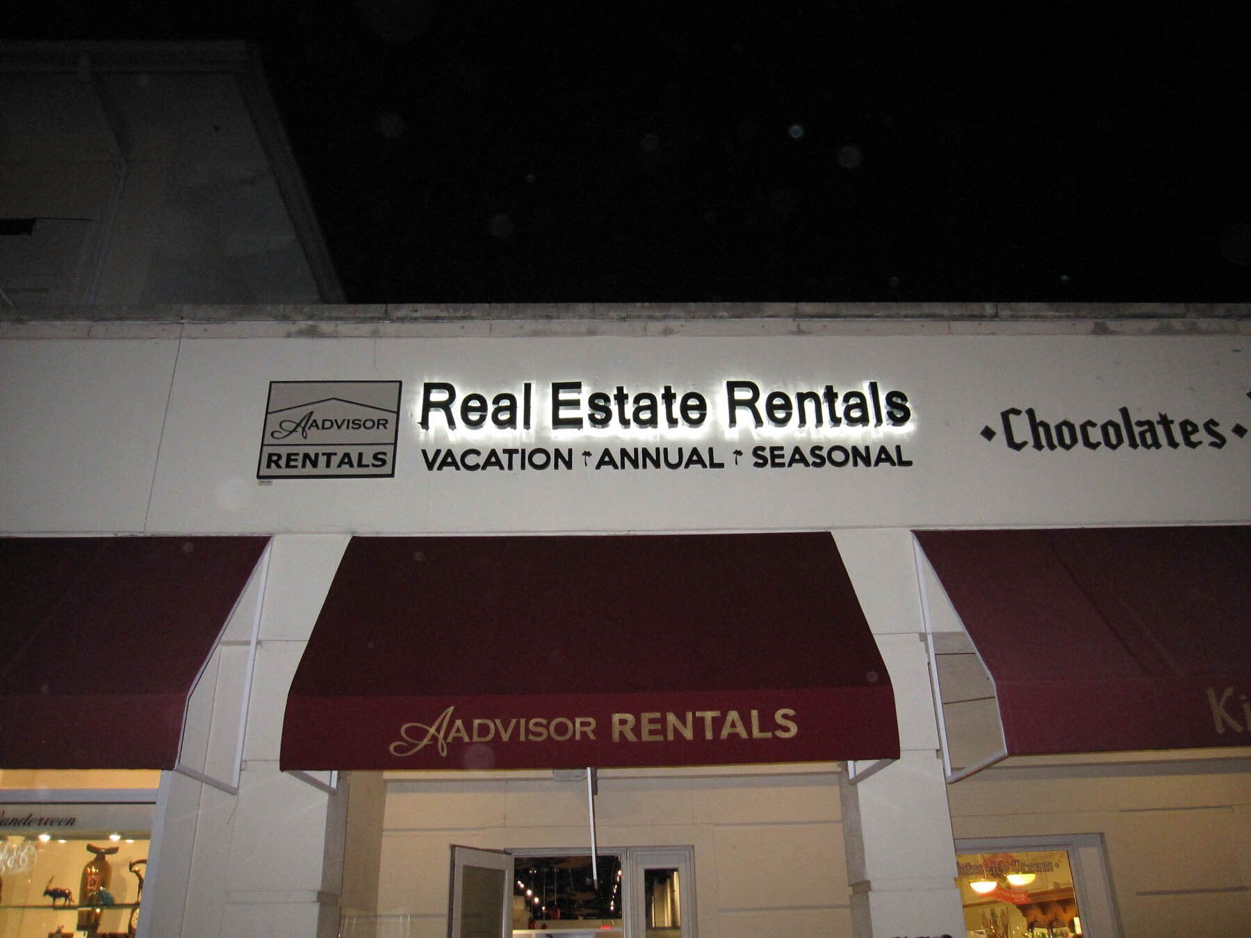 A sign for real estate rentals with a red awning