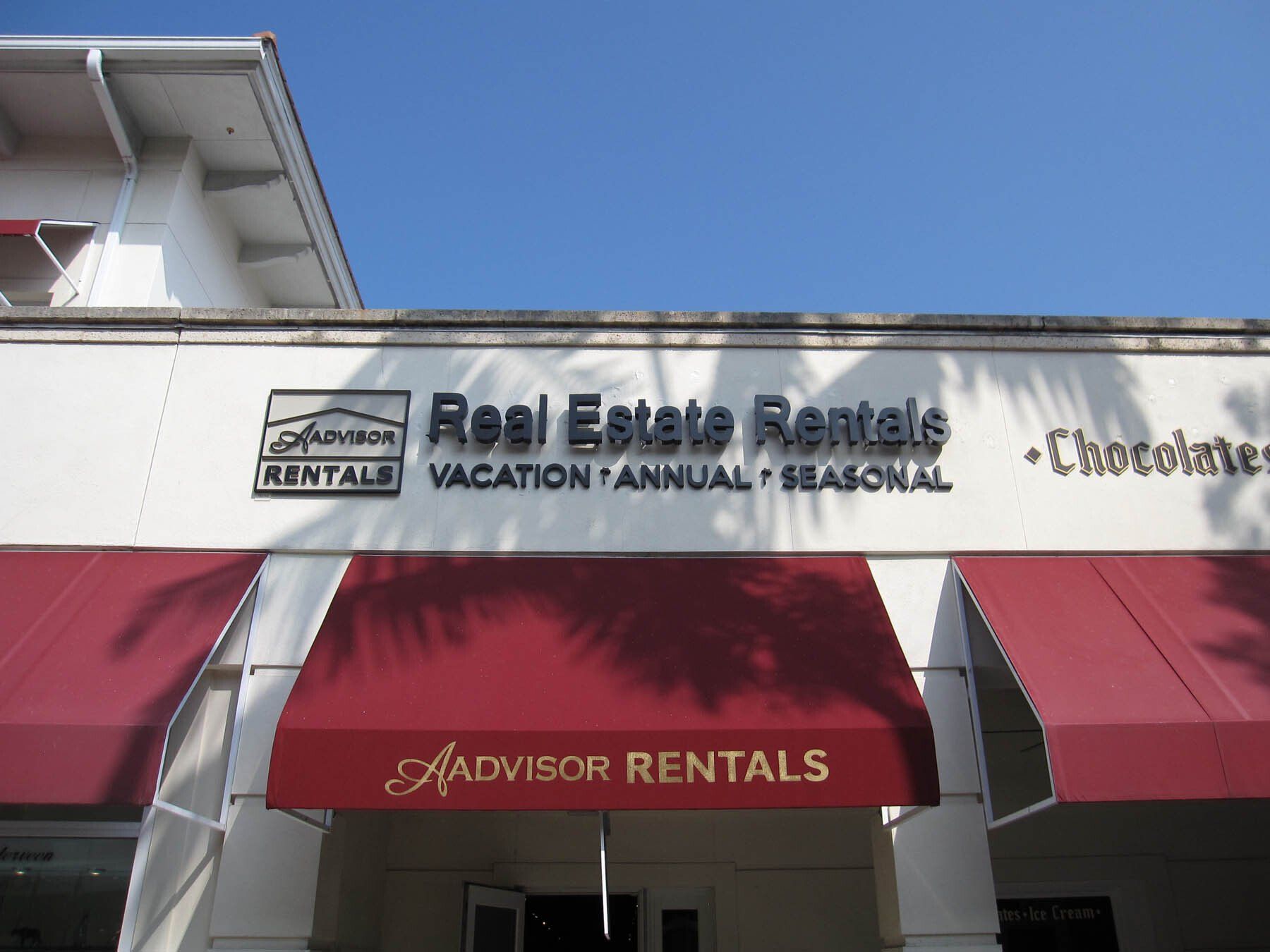 A sign for real estate rentals with a red awning