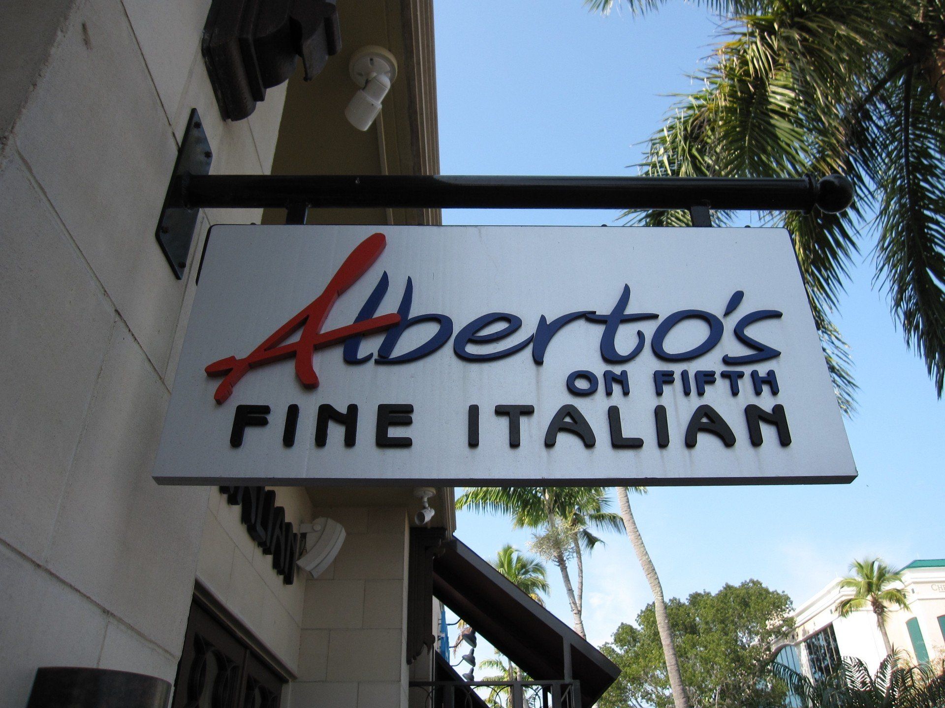 A sign for alberto 's fine italian hangs from the side of a building