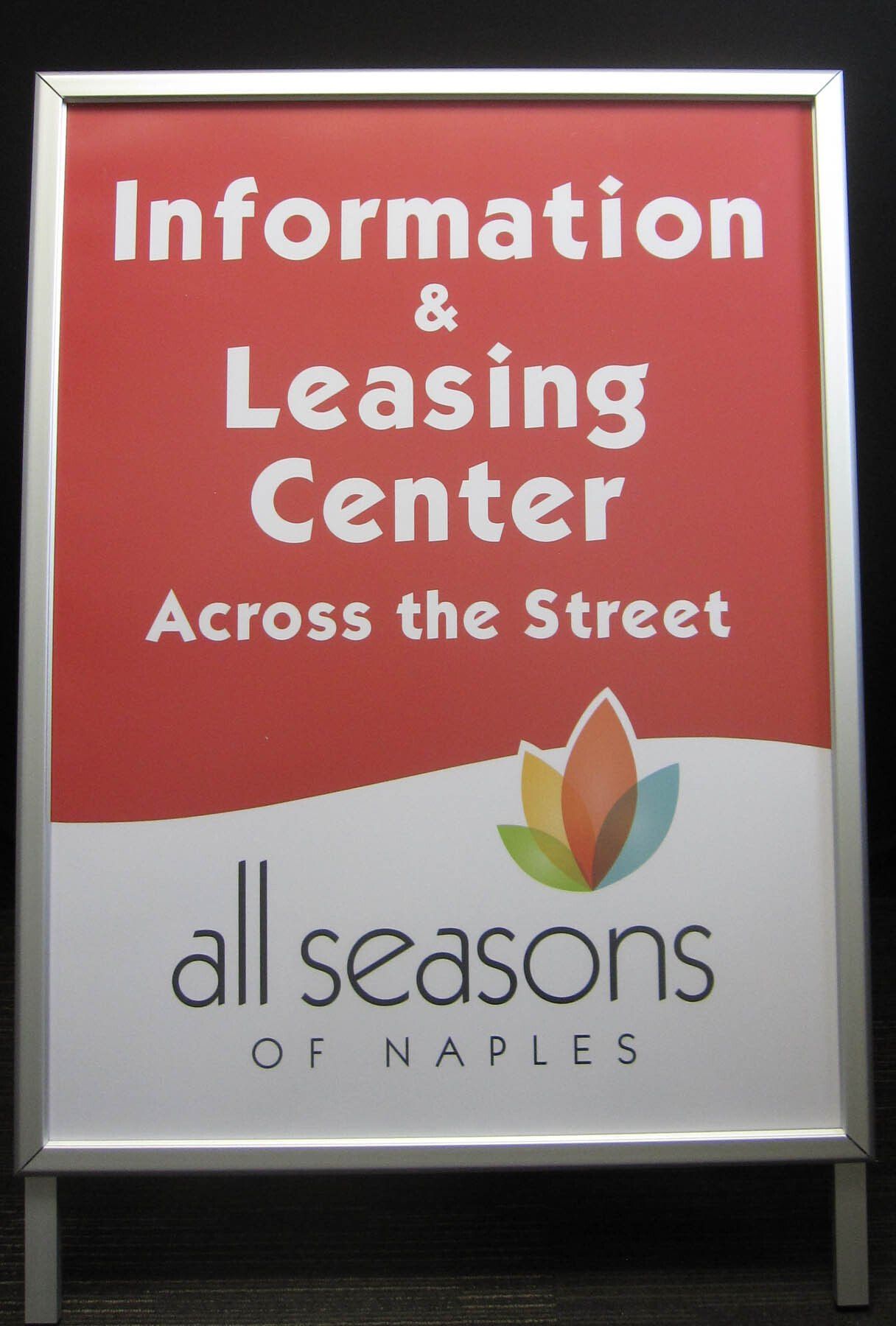 A red sign that says information and leasing center across the street